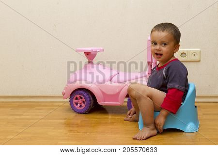 Smiling Child Sitting On Chamber Pot Indoors