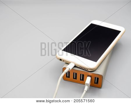 Smart phone charging with multiport USB power adaptor on gray background with copy space Selective focus