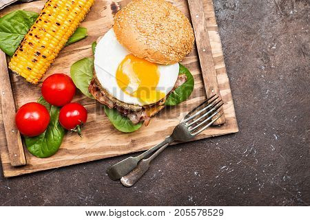 Homemmade Bacon Hamburger with fried Egg, Lettuce and lentil burger with a garnish of corn and tomatoes, top view