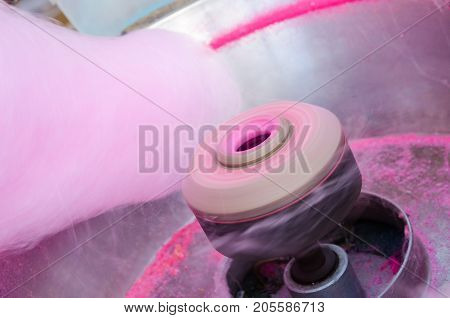 Hand rolling cotton candy in candy floss machine.