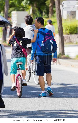 OSAKA JAPAN - SEPTEMBER 18 : unidentified asian little girl riding a unicycle (one wheel bike) with her father in a park on September 18 2017 in Osaka Japan.