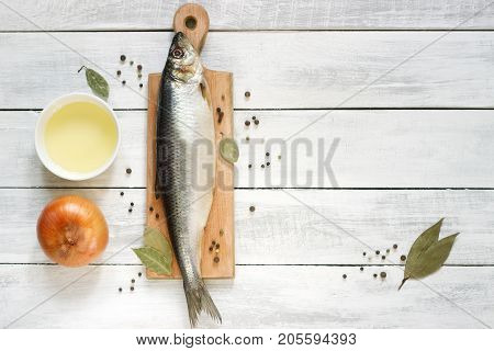 Herring with onions vegetable oil and spices on a wooden board. The background. Rustic style selective focus.