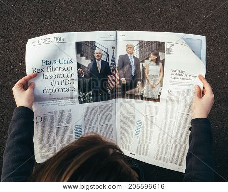 PARIS, FRANCE - SEP 25, 2017: Woman reading international newspaper about Donald Trump, Rex Tillerson and Nikki Halley