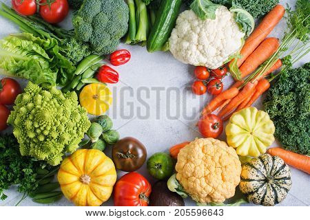 Colorful vegetables arranged in a circle on the light grey background, copy space for text in the middle, selective focus