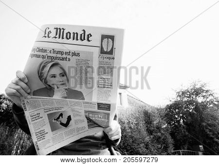 PARIS; FRANCE - SEP 24; 2017: View from below of woman reading latest newspaper Le Monde with portrait of Hillary Clinton on cover about how Donald Trum has lost the moral leadership of United States