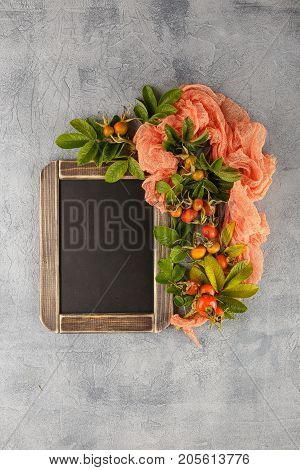 Blackboard and dogrose berry Autumn decorations. Top view space for text on the board.