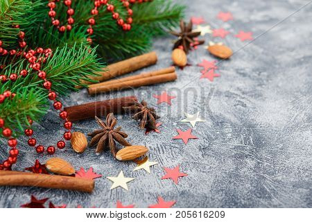 Christmas background with spruce branches decorations and spices - cinnamon anise stars dried oranges and almonds