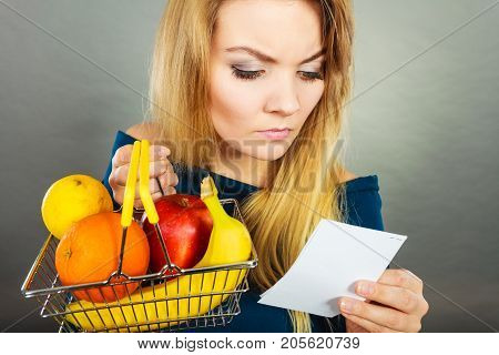 Worried Woman Holding Shopping Basket With Fruits