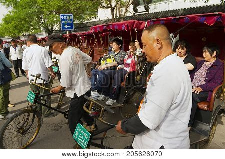 BEIJING, CHINA - MAY 01, 2013: Unidentified rickshaws transport passengers at Futong street next to the Houhai lake in Beijing, China.