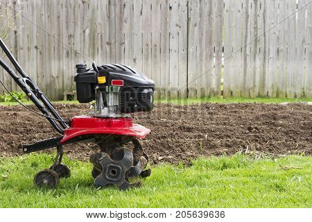 a tiller machine plowing a garden in spring.