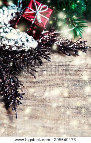 Christmas Card with Christmas gifts fir tree branches xmas holiday decorations festive symbols and falling snow on bright wooden background with copyspace
