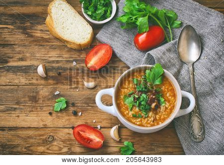 kharcho soup rice beef tomatoes herbs in white bowl piece of bread on old wooden table canvas traditional Georgian cuisine top view