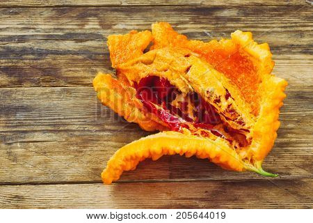 ripe opened fruit of momordica on wooden table macro image
