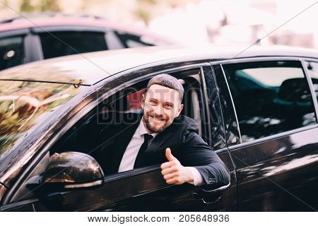 Handsome Young Beatded Businessman In A Car With Thumbs Up