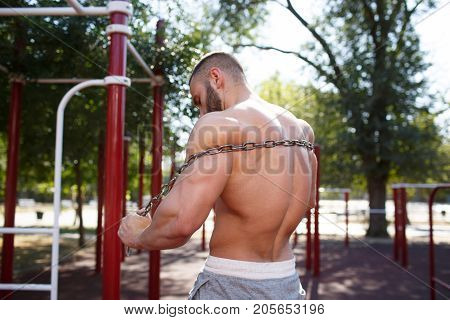 Sporty and healthy muscular man exercising outdoors. Sexy young man with a muscular body on a natural background. Strong and perfect male body.