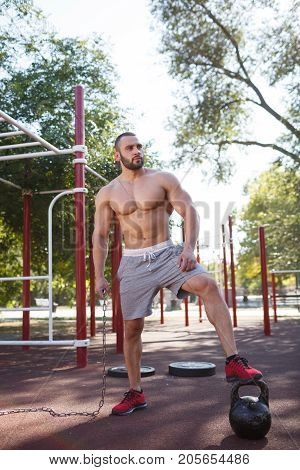 Sporty and healthy muscular man exercising outdoors. Sexy young man with a muscular body on a natural background. Strong and perfect male body.
