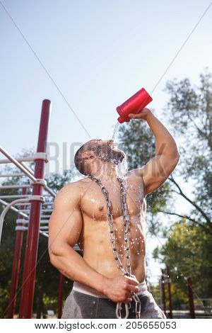 Sporty and healthy muscular man exercising outdoors. Sexy young man with a muscular body on a natural background. Strong and perfect male body.