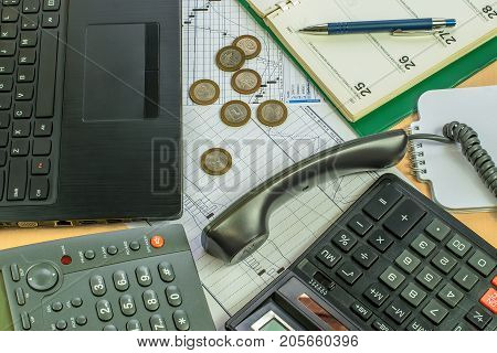 Business office, telephone, notebook, computer, calculator, graphics, pen.