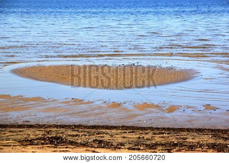Calm shallow sea and  heart-shaped sand in the water