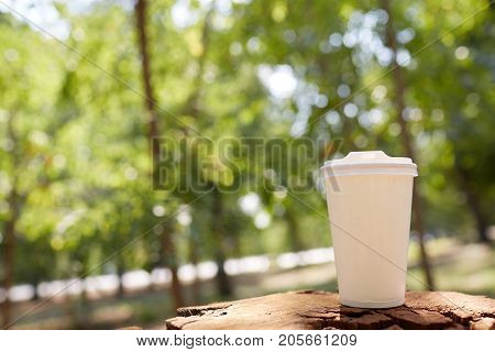White glass with tea stands on a stump on a sunny autumn background. Close-up.