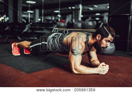 Plank it. Confident muscled young man wearing sport wear and doing plank position while exercising in gym.