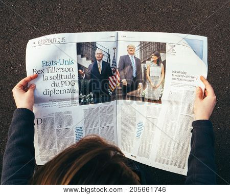 PARIS FRANCE - SEP 25 2017: Woman reading international newspaper about Donald Trump Rex Tillerson and Nikki Halley