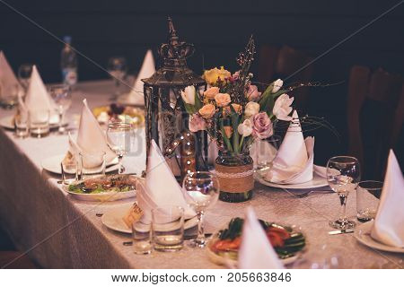 Elegant Restaurant Table with flowers, decor and dishes in studio