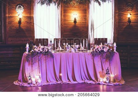 Table for bride and groom with decor, candles flowers and dishes in hall