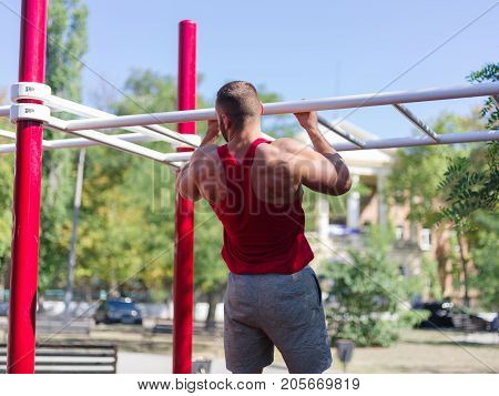 Sporty and healthy muscular man exercising outdoors. Sexy young man with a muscular body on a natural background. Strong and perfect male body.