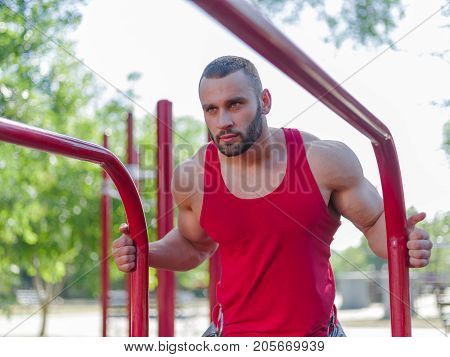 Sporty and healthy muscular man exercising outdoors. Sexy young man with a muscular body on a natural background. Strong and perfect male body.