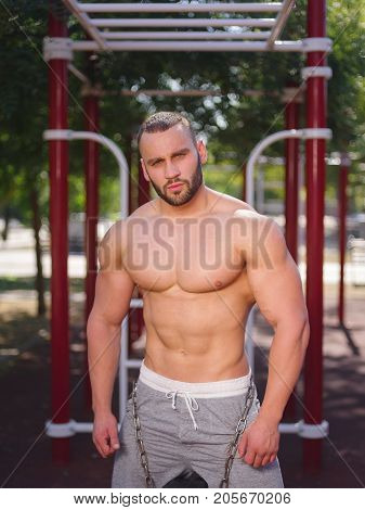 Sporty and healthy muscular man exercising outdoors. Sexy young man with a muscular body on a natural background. Strong and perfect male body.