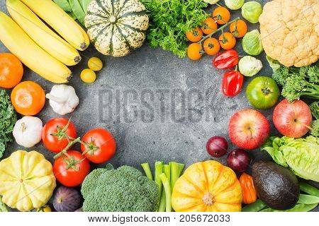 Different vegetables and fruits arranged in a circle on the dark grey background, copy space for text in the middle, top view, selective focus