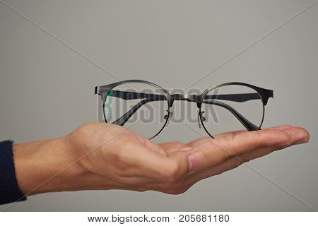 Glasses on human lay hand close up isolated on gray background