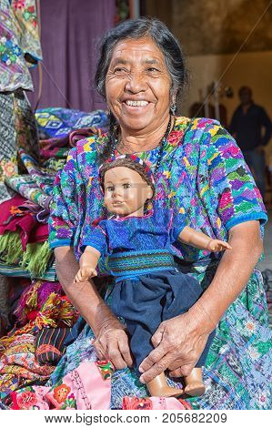 February 14 2015 Antigua Guatemala: mayan woman in traditional dress holding a doll at a local artisan market