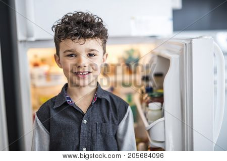 A Young white boy standing in front of open refrigerator.