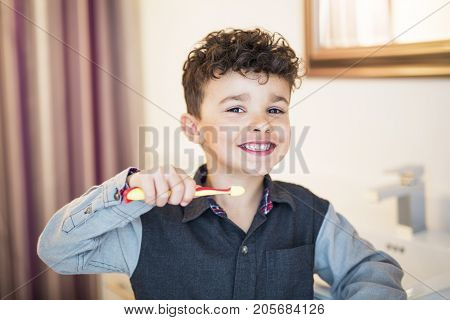 A kid boy brushing teeth on the bathroom
