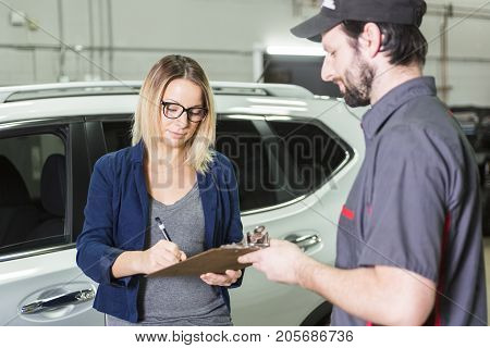 An auto mechanic and female customer in garage