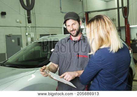 An auto mechanic and female customer in garage