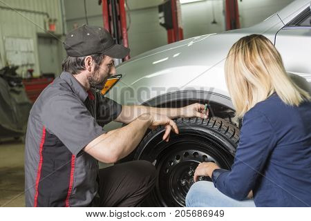 An auto mechanic and female customer in garage