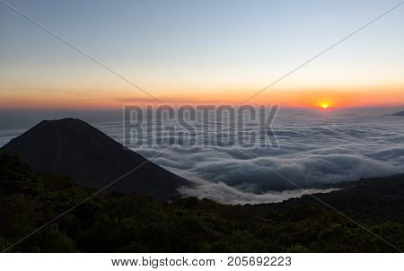 the volcano Izalco rising above clouds at sunset in Cerro Verde national park El Salvador