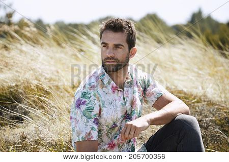 Handsome guy with stubble and floral shirt looking away