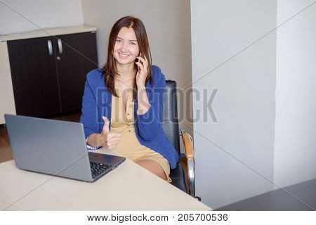 cute young office worker talking on cell phone in office.