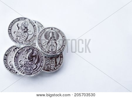 On a gray background are silver coins of an investment silver from a British mints. Dragon of Wales Lion of England and Griffin of Edward III. Empty space for text input.