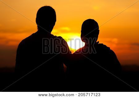 Two male friends or homosexual couple enjoying sunset time together. Relaxation and leisure concept.