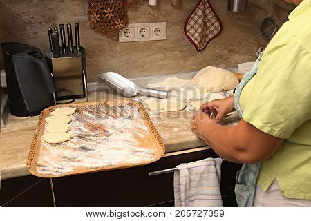 Senior woman baking pies in her home kitchen.Grandma cooks pies. Home cooked food. omemade mold cakes of the dough in the women's hands. The process of making pie dough by hand.