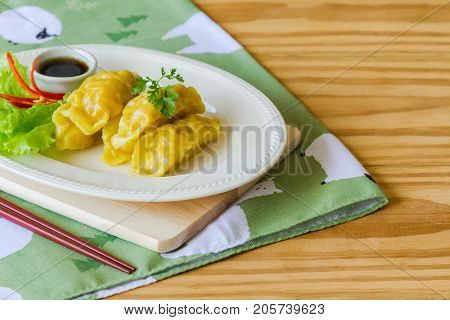 Homemade minced pork dumpling on white plate served with dipping soy sauce on wood table with copy space. Delicious dumpling or dim sum for breakfast or dinner. Dim sum or dumpling is Chinese food. Dumpling or dim sum ready to served.