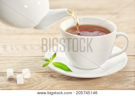 cup with green tea and teapot on light wooden table background