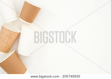 Craft and white disposable cups on white background. Top view geometry.