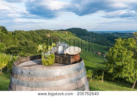 Jars with grapes and candle on wooden barrel near vineyard on south Styrian wine route in Austria