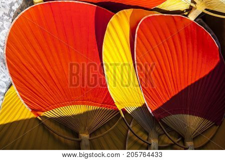 Setting of handheld fans for wedding guests. Red and yellow bamboo rigid fans